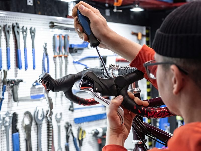 Mechaniker stellt in der Werkstatt die Bremse eines Velos ein